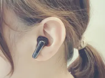 女性が左耳にQCY MeloBuds N70を装着している