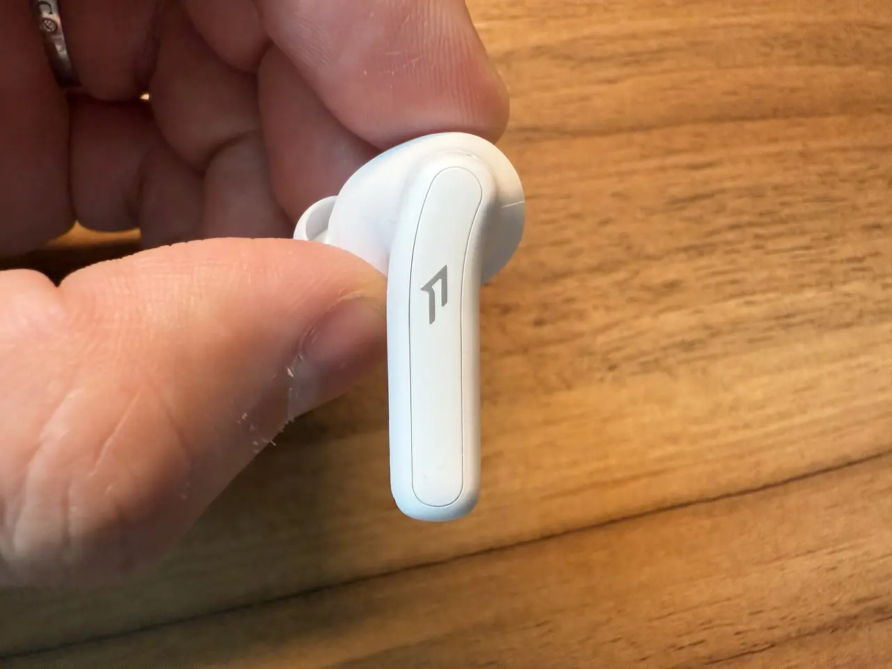 1MORE Q21のイヤホン単体を指で摘まんでいる(側面アングル)