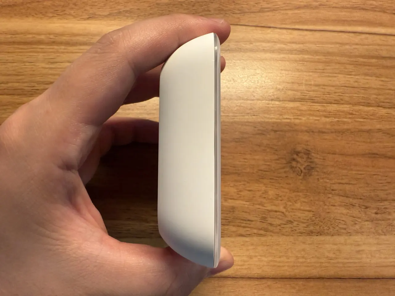 SwitchBot 温湿度管理パネルを指で掴んでいる(側面アングル)