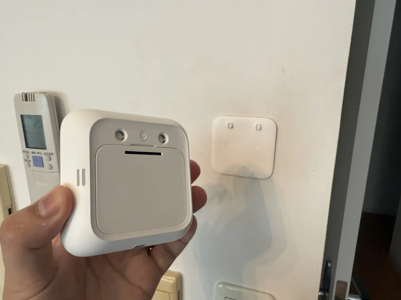 SwitchBot 温湿度管理パネルを手に持っている