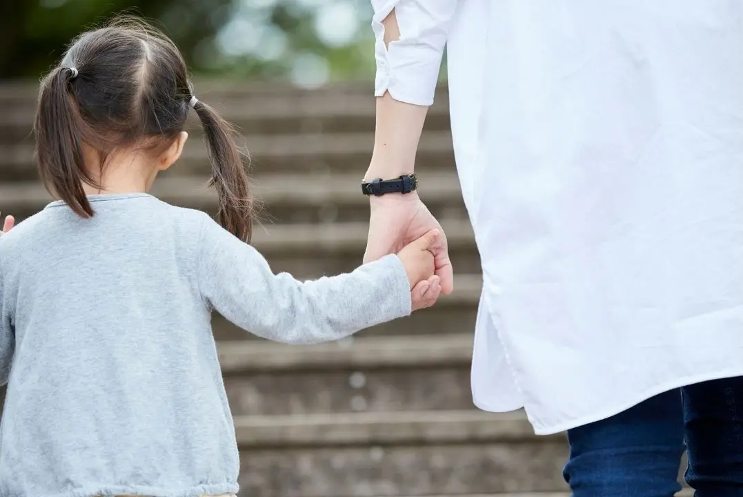 大人と手をつなぐ子供の後ろ姿