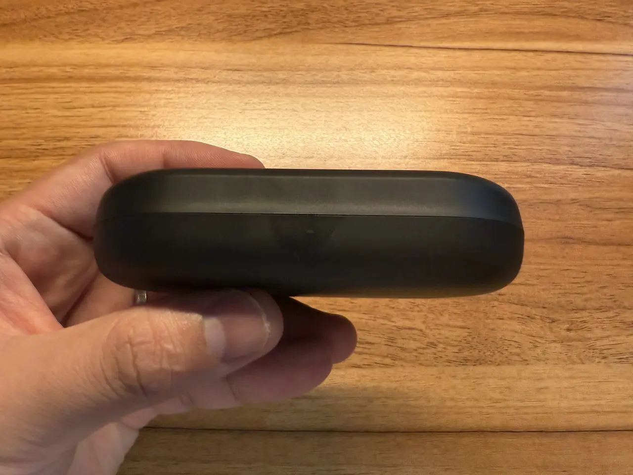 OpenRock Link 20の充電ケースを指で摘まんでいる様子(側面アングル)