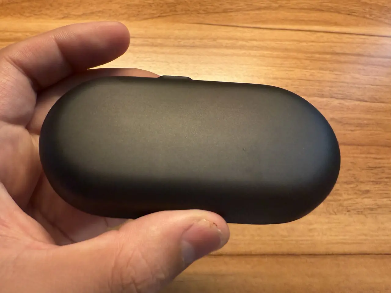 OpenRock Link 20の充電ケースを指で摘まんでいる様子(底部アングル)