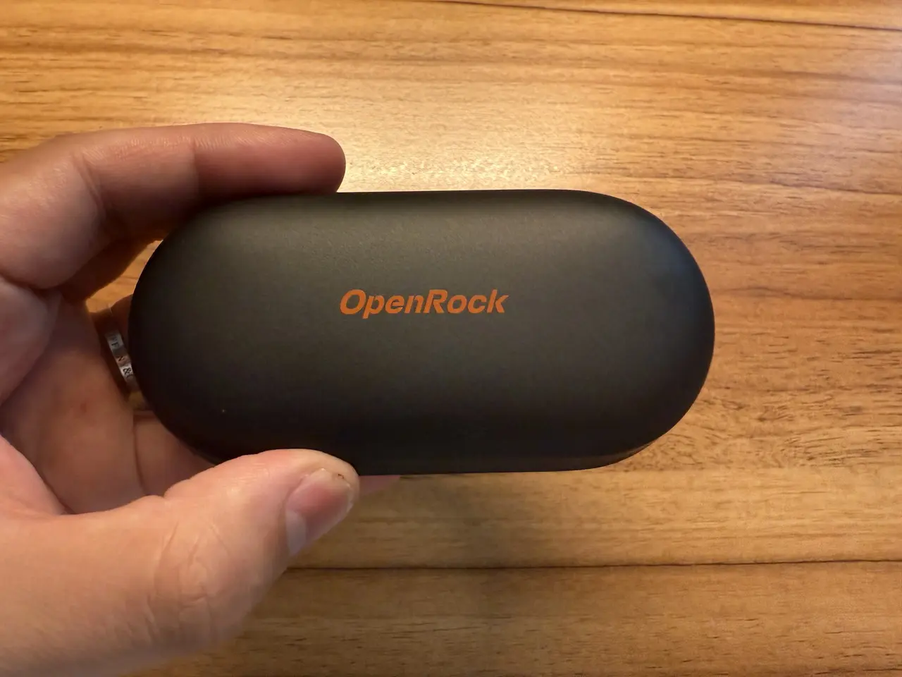 OpenRock Link 20の充電ケースを指で摘まんでいる様子(真上アングル)