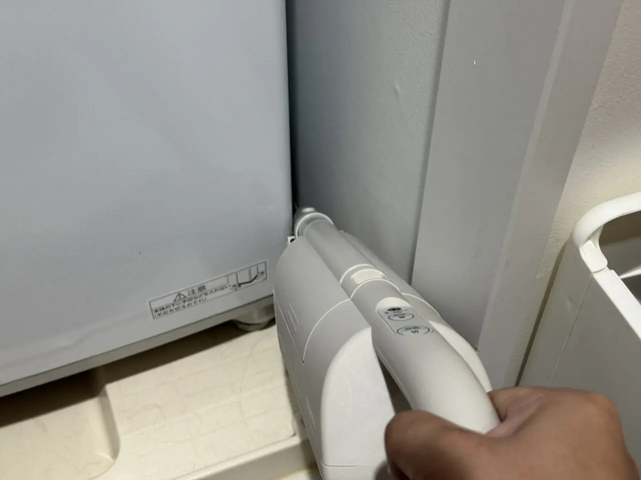 すき間ノズルで洗濯機の隙間を掃除している様子