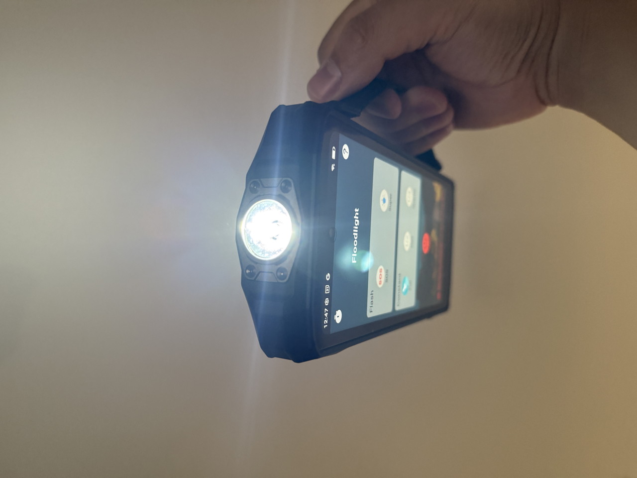 ハンドストラップホルダーを装着した状態のFossibot F113を手に持って点灯させている様子