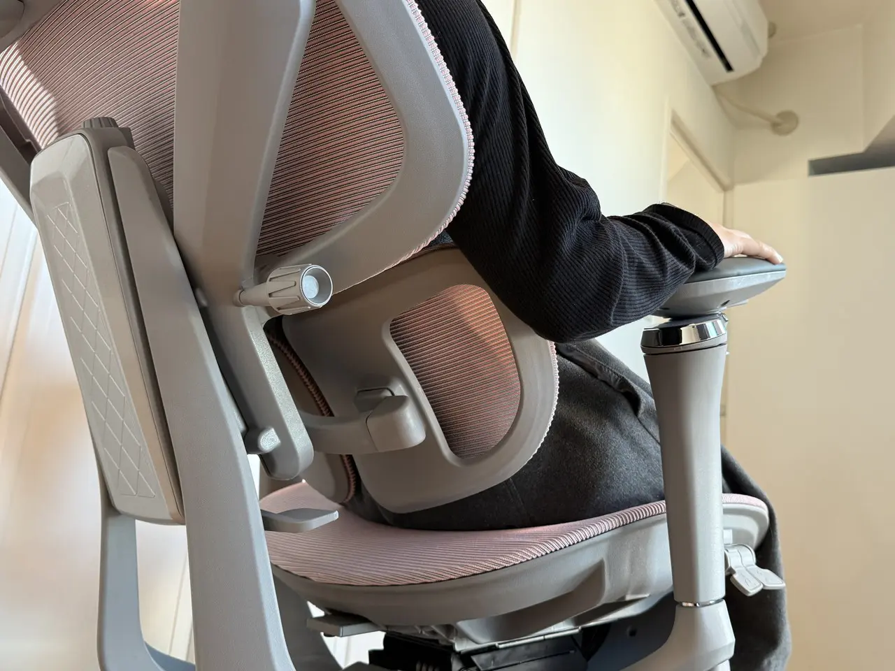 女性がCAGUUU AXIS エルゴコアオフィスチェアに腰かけている(背面下アングル)
