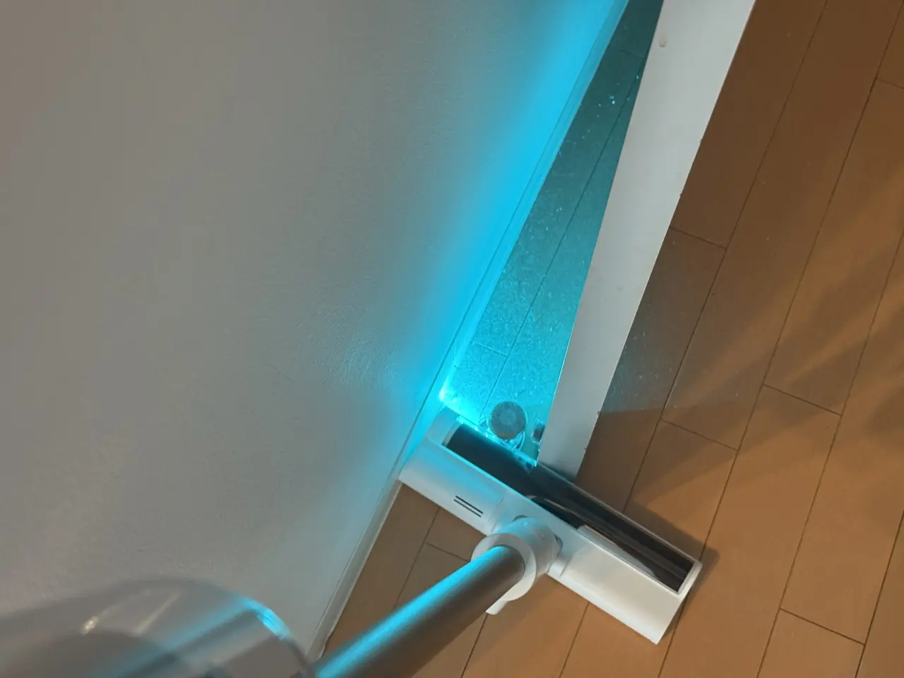 Dreame X1 Air コードレス掃除機のLEDライトでドアの隙間のホコリを照らし出している様子