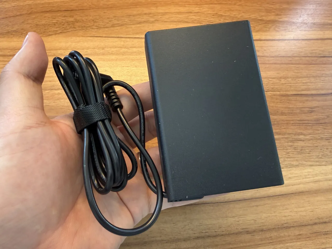 GEEKOM A9 MAX 2026の電源アダプタを手に持っている