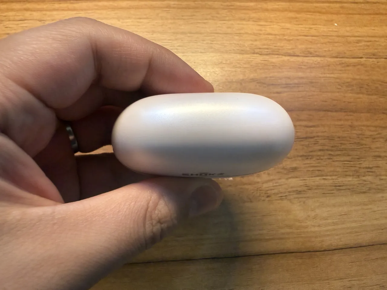 Shokz OpenDots 2の充電ケースを指で摘まんでいる