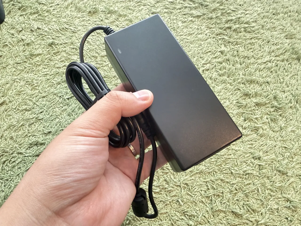TCL A1sの電源アダプタを手に持っている