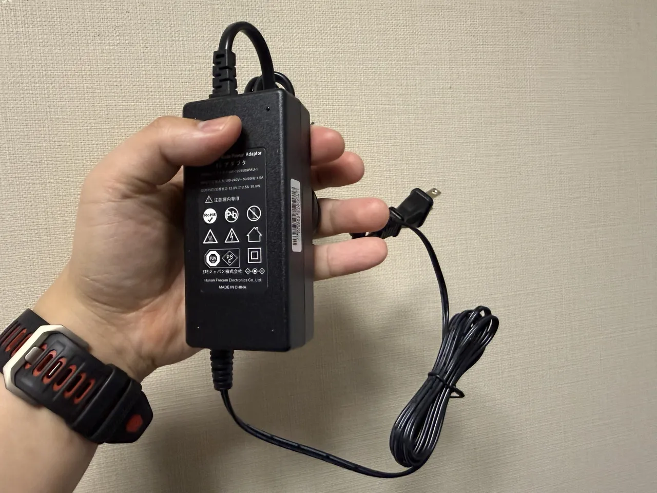 電源アダプタを手に持っている