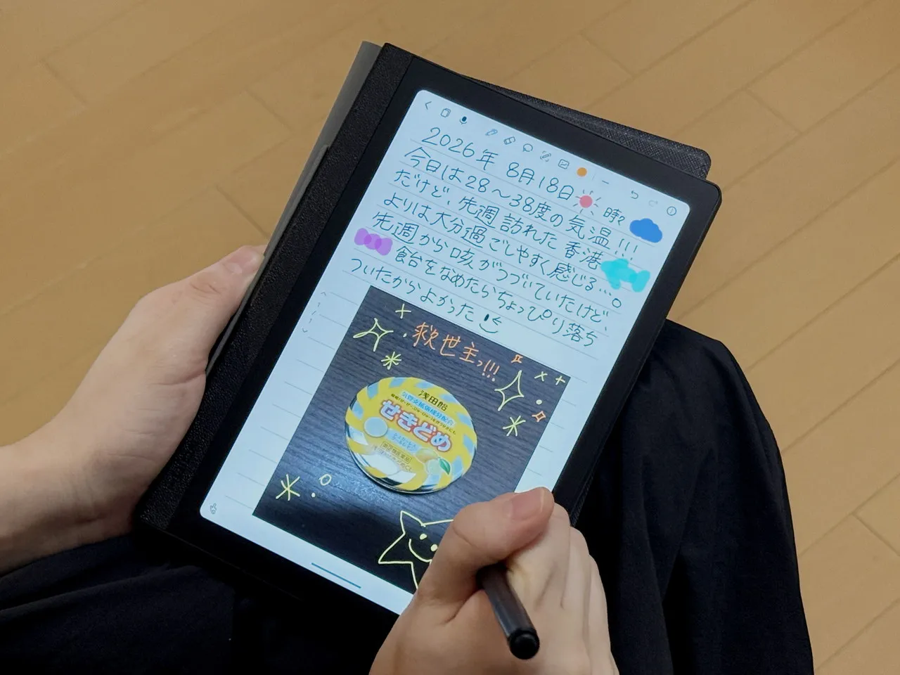 Huion Note Eを手に持って文字を描いている
