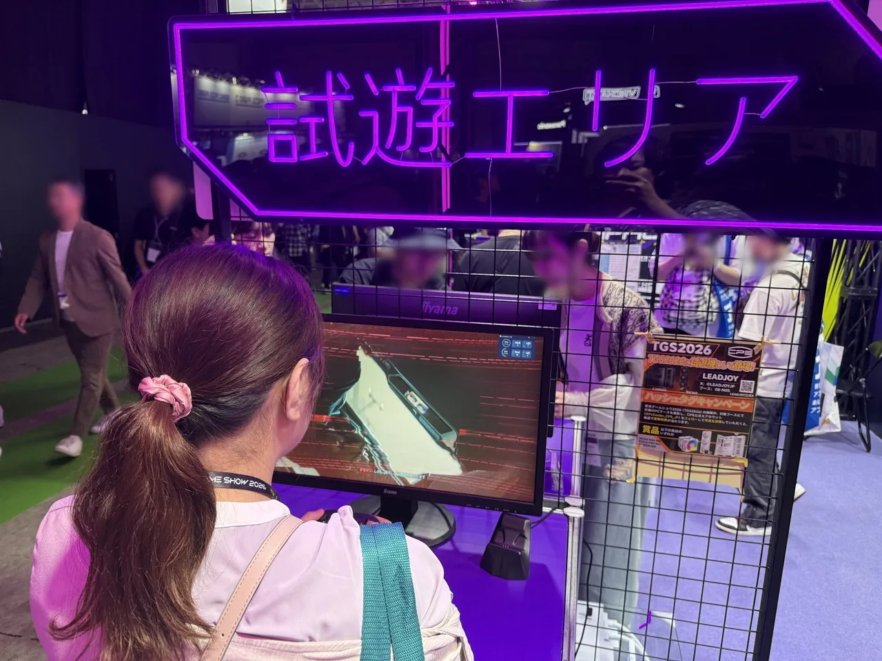 LeadJoyブースの試遊エリアでゲームを操作する撮影担当スタッフ