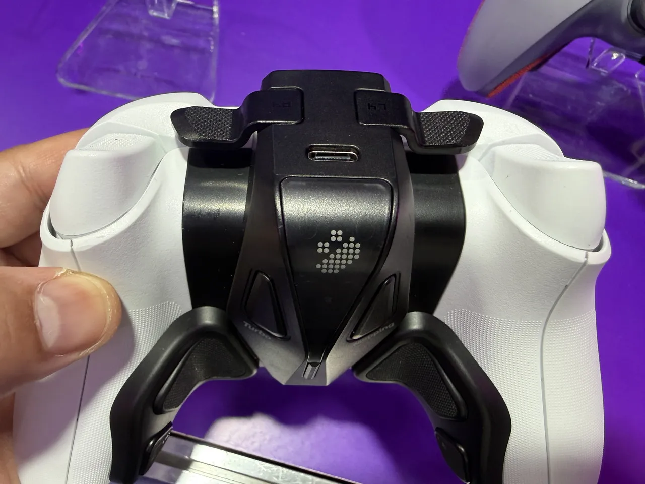 白いゲームパッドの背面と中央に取り付けられたパーツを確認する様子