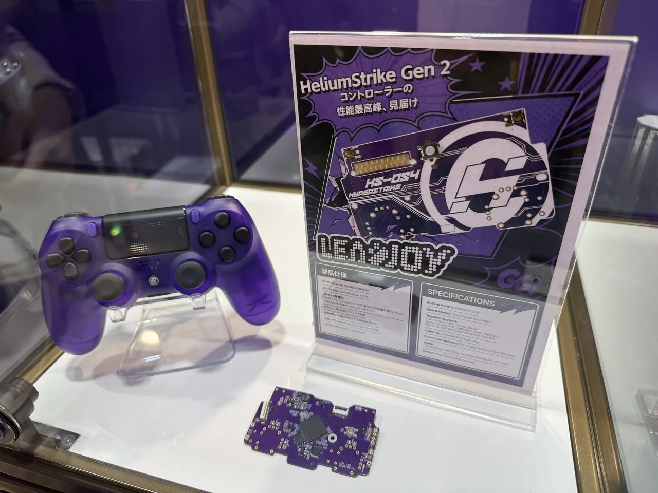 HeliumStrike Gen 2の説明パネルとゲームパッド、基板を並べた展示
