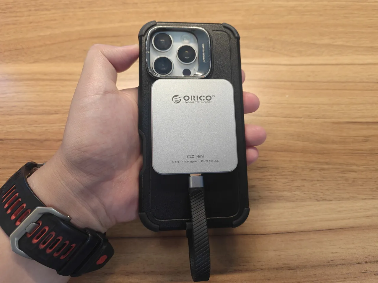 ORICO K20 Miniを装着したiPhone 16 Proを手に持っている(背面アングル)