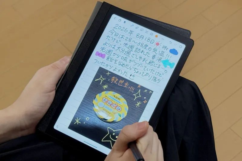 Huion Note Eを手に持って文字を描いている